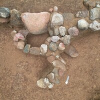 Ułożony z kamieni symbol trykwetry odkryty w kurhanie. Fot. Sławomir Wadyl / A symbol of a triskelion made of stones discovered in a burial mound. Photo. Sławomir Wadyl